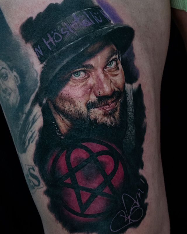A detailed tattoo of a man wearing a hat with the word 